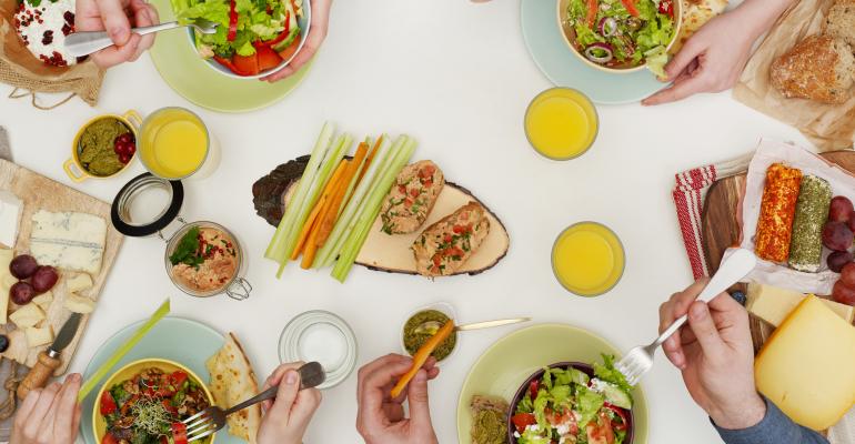 Hands reaching for colorful food at a table