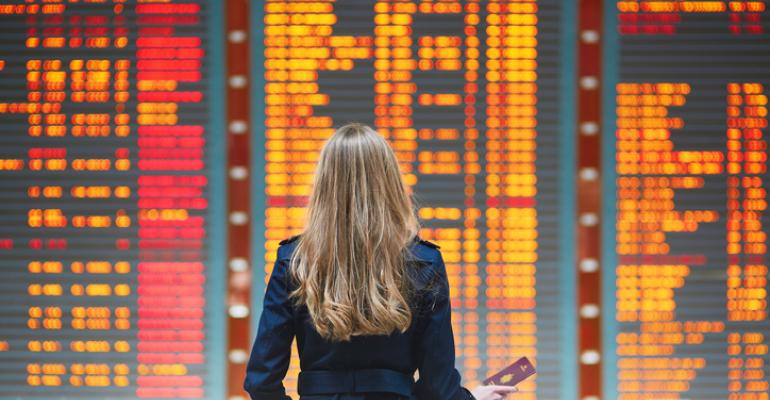 Woman traveler in front of international airport departure board