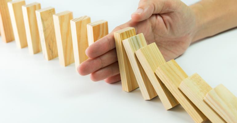 Solution concept with hand stopping wooden blocks from falling in the line of domino