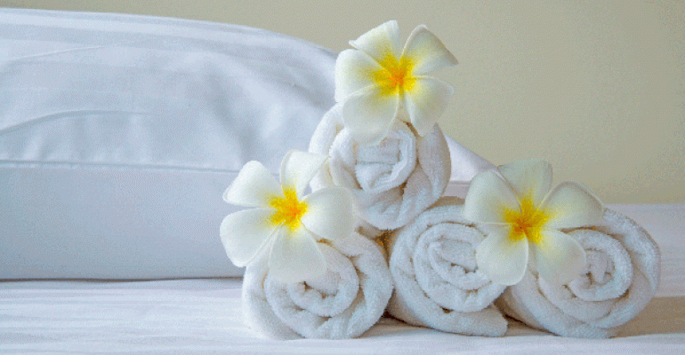 towels rolled up on hotel bed with flowers
