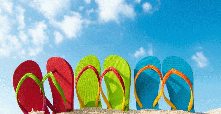 Three pairs of colorful flip flops against blue sky