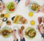 Hands reaching for colorful food at a table