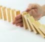 Solution concept with hand stopping wooden blocks from falling in the line of domino