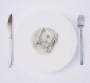 Dollars on a plate with knife and fork