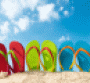 Three pairs of colorful flip flops against blue sky