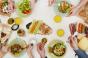 Hands reaching for colorful food at a table