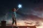 Boy on rooftop touching a star
