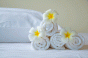 towels rolled up on hotel bed with flowers