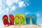 Three pairs of colorful flip flops against blue sky